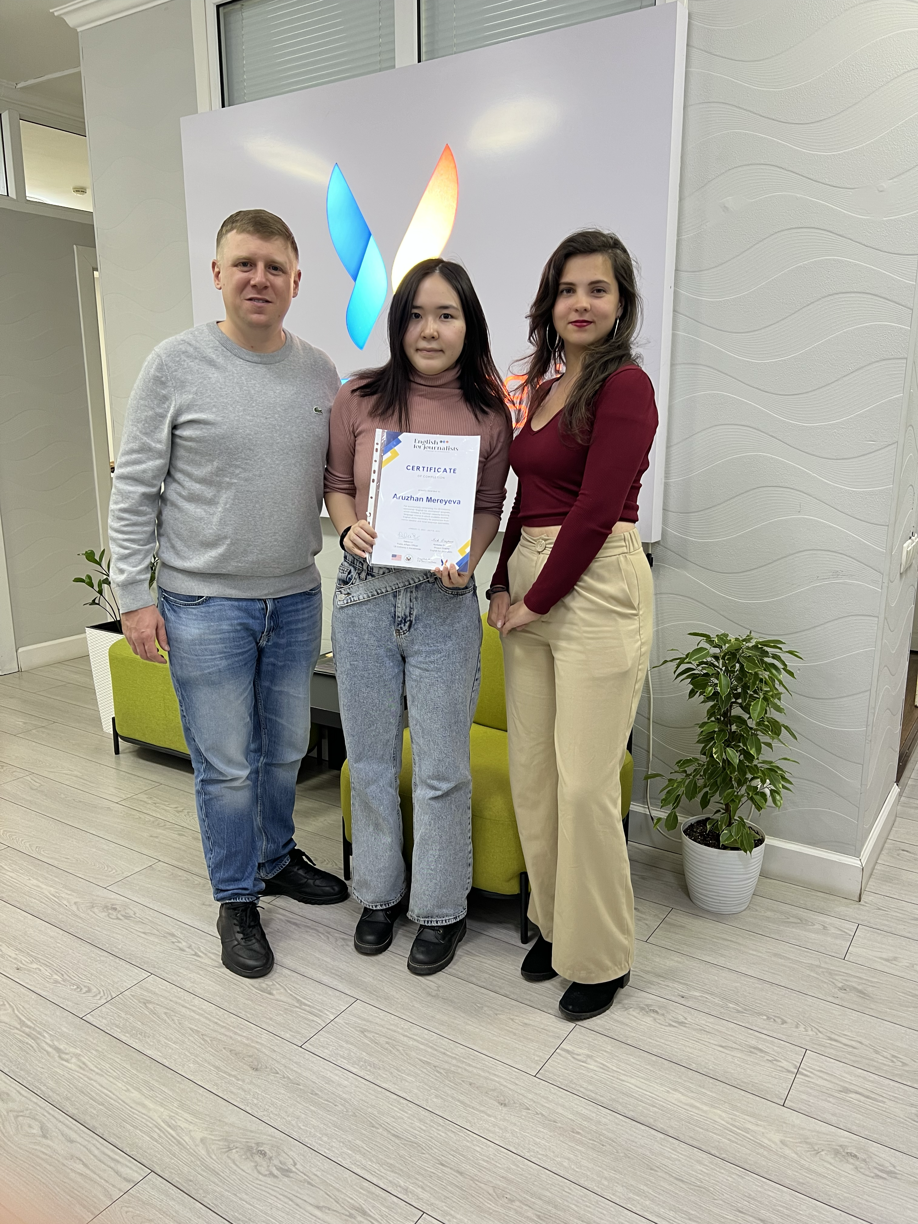 Три человека у логотипа NLE с сертификатом об обучении
